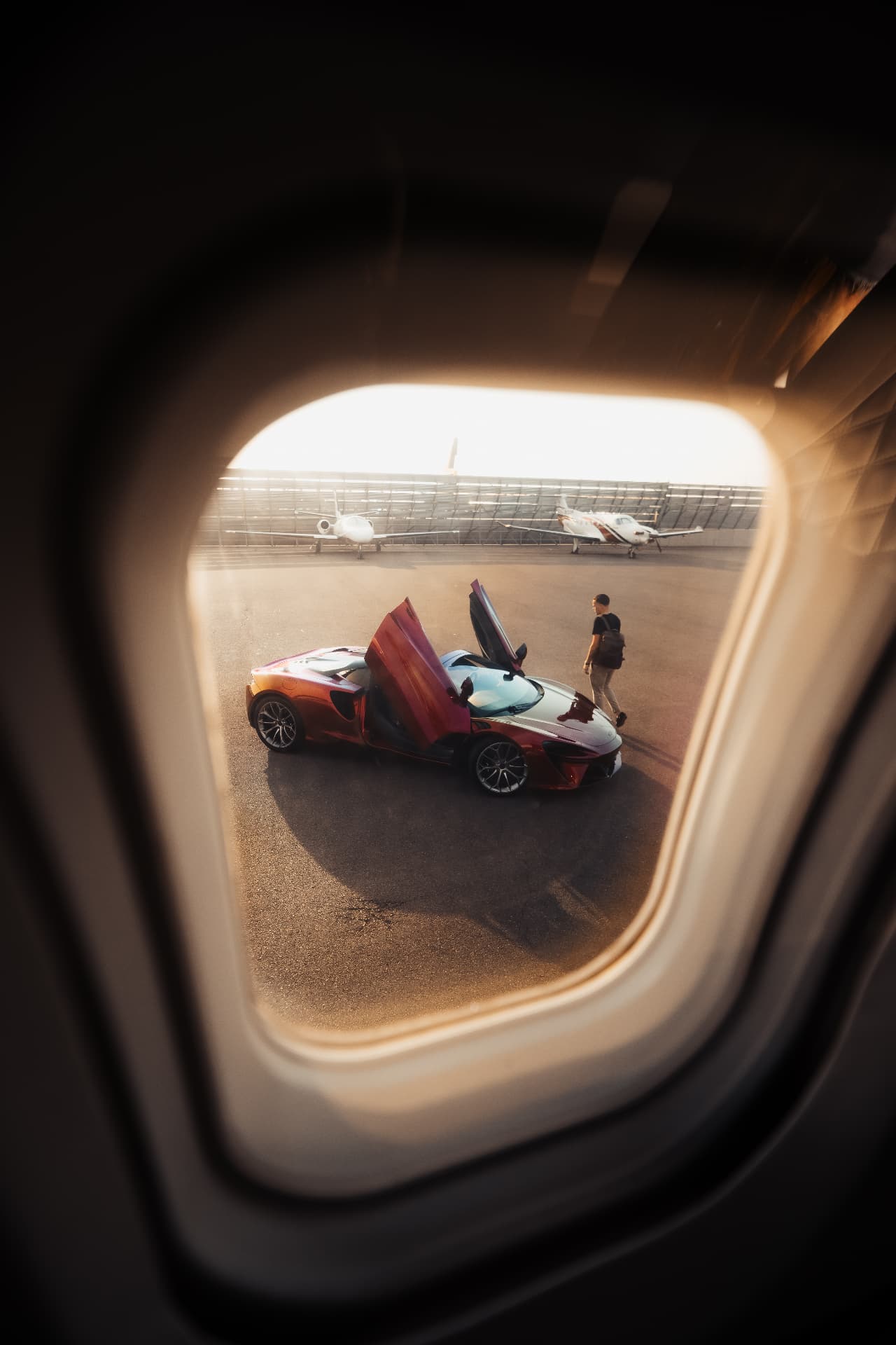 View of a McLaren on the tarmac through a private jet window