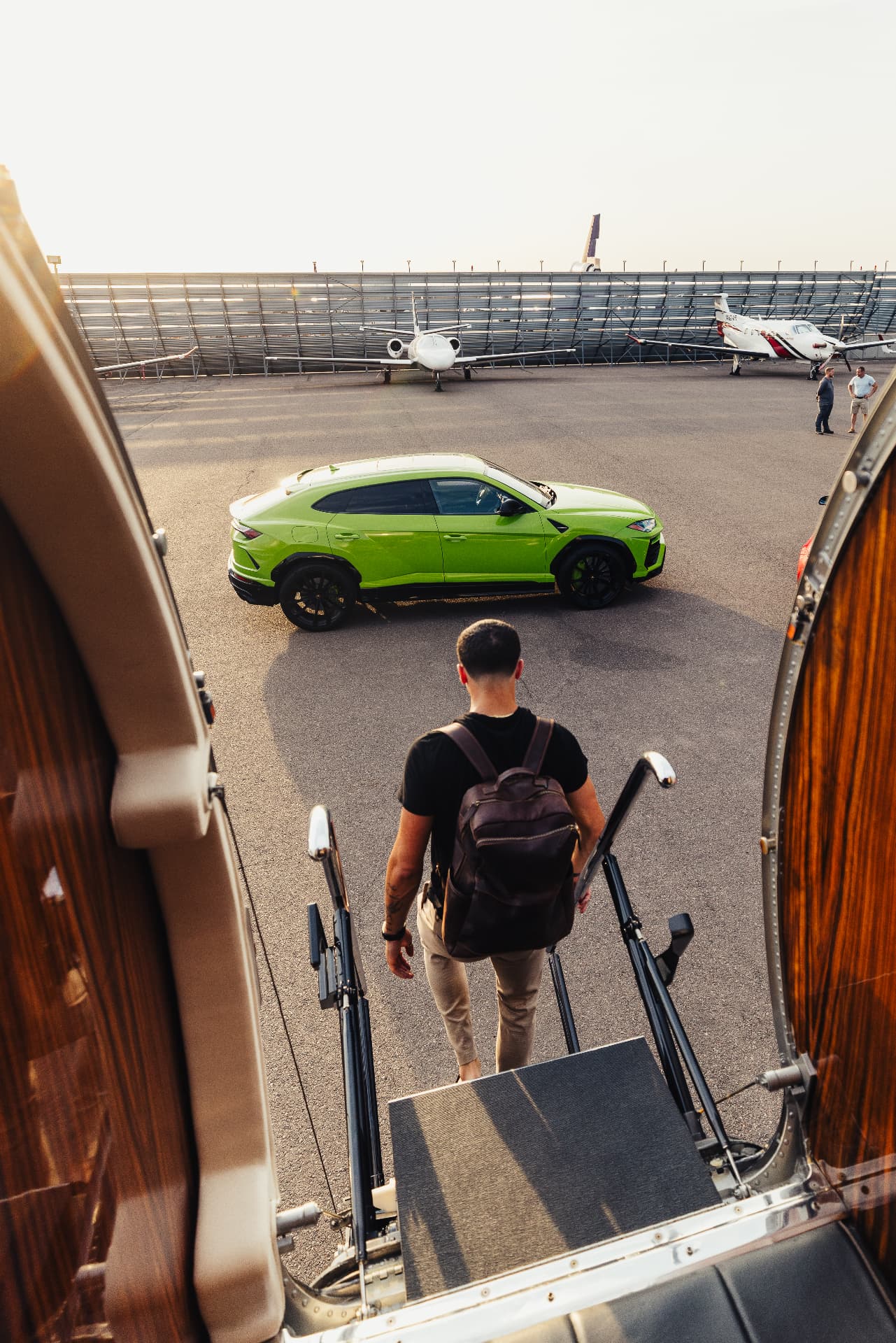 Passenger deplaning toward a Lamborghini Urus waiting on the tarmac