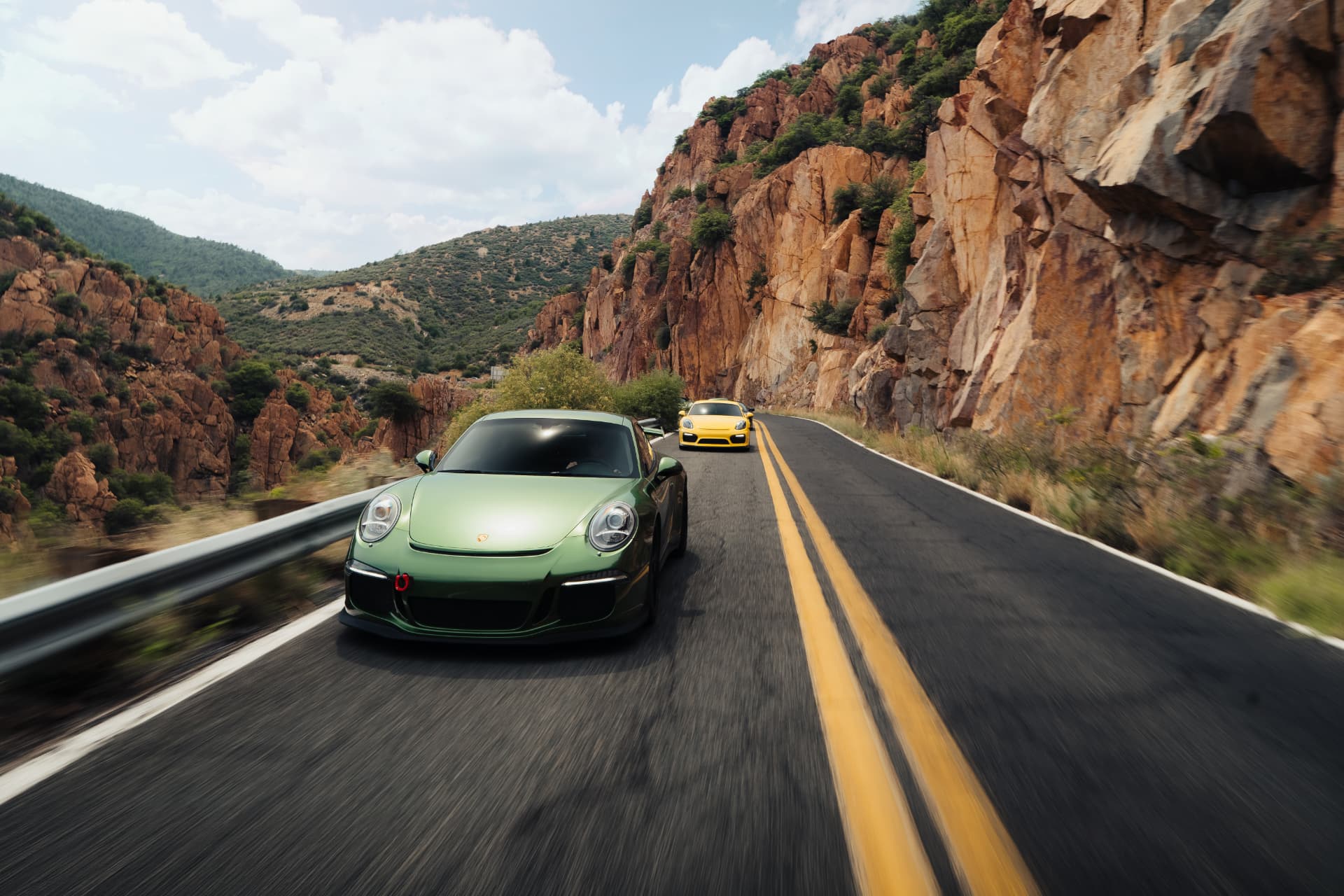 Green Porsche 911 GT3 leading through a red rock canyon